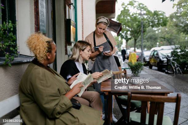waitress taking order from customers sitting outside restaurant - ober stockfoto's en -beelden