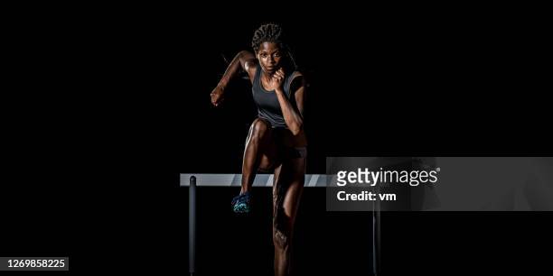 african-american woman running away from a hurdle - runner front view stock pictures, royalty-free photos & images