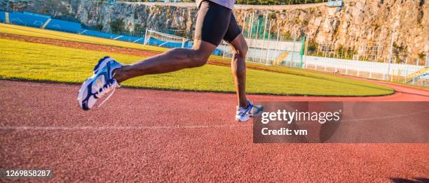 man running on a running track next to a football field - sprint stock pictures, royalty-free photos & images