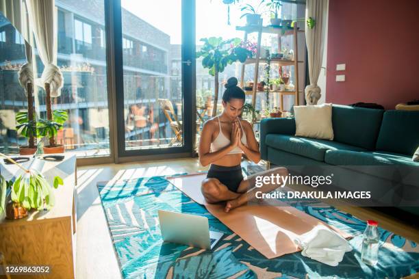 beautiful girl practicing yoga and using laptop at home, copy space - lotus position - fotografias e filmes do acervo