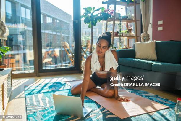 a young sports woman exercising using a laptop - heimtraining stock-fotos und bilder