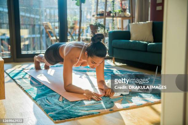 young sporty woman practicing at home - postura de plancha fotografías e imágenes de stock