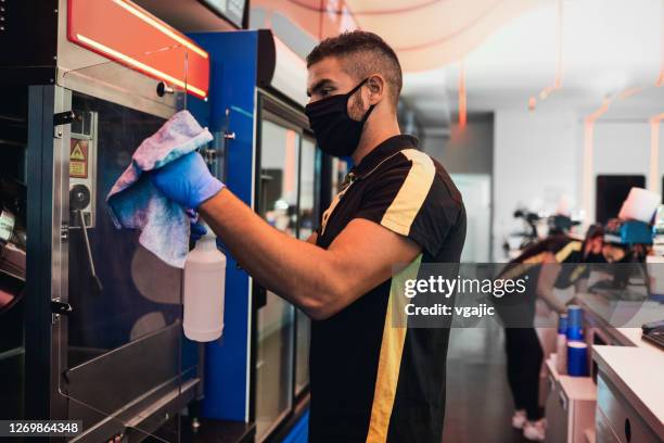 employees cleaning movie theater for reopening after coronavirus pandemic. male employee cleaning popcorn maker - office space movie stock pictures, royalty-free photos & images