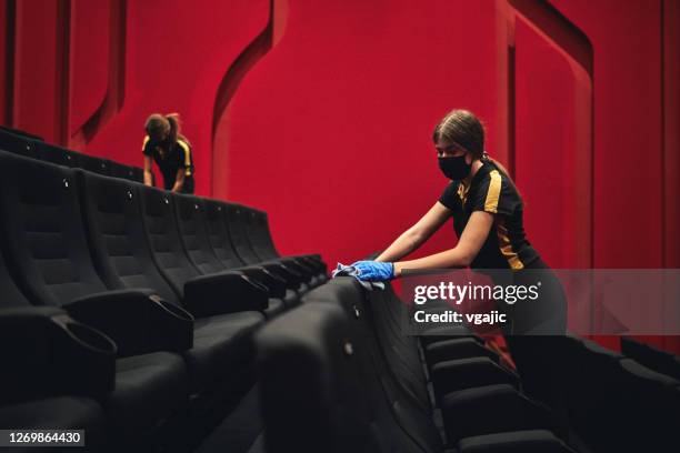 female employees disinfecting movie theater seats before reopening after coronavirus pandemic - office space movie stock pictures, royalty-free photos & images