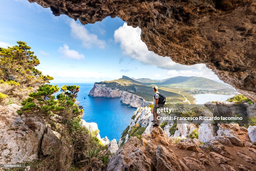 Capo Caccia, hiker admiring the view from a cave. Sardinia, Italy