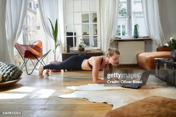 young woman using laptop for doing home workout - postura de plancha fotografías e imágenes de stock