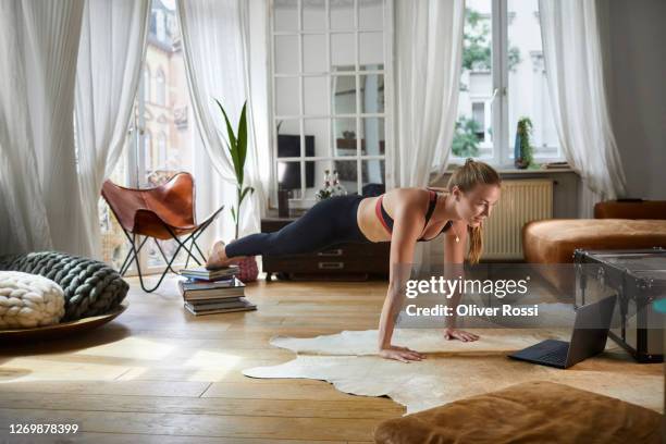 young woman using laptop for doing home workout - flexiones fotografías e imágenes de stock