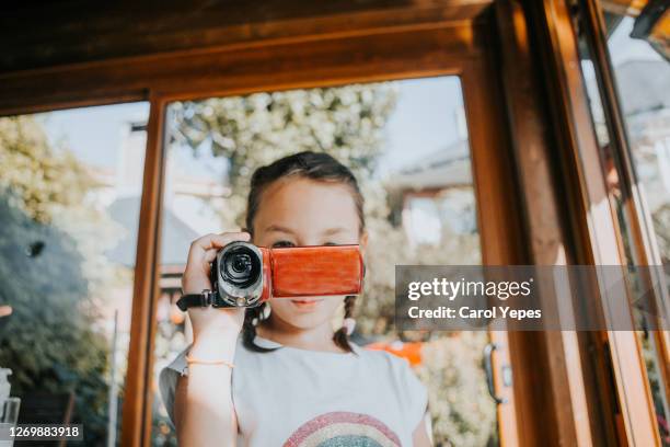 girl (10) in braids filming with video camera to her family during summer day - camera girls stock pictures, royalty-free photos & images
