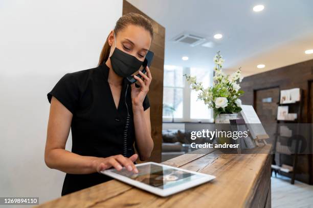mujer trabajando en un spa con una máscara facial mientras habla por teléfono - spa treatment fotografías e imágenes de stock
