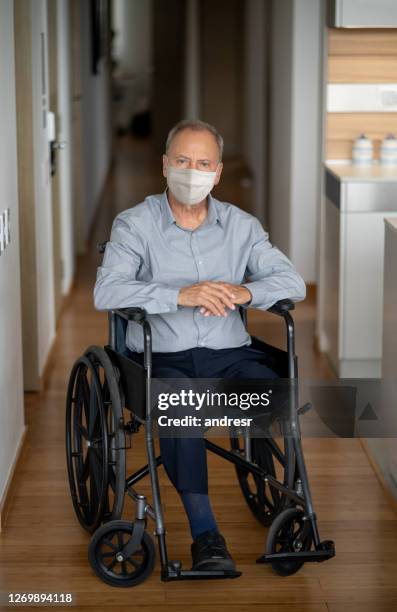 disabled senior man in a wheelchair wearing a facemask at home - diabetic amputation stock pictures, royalty-free photos & images