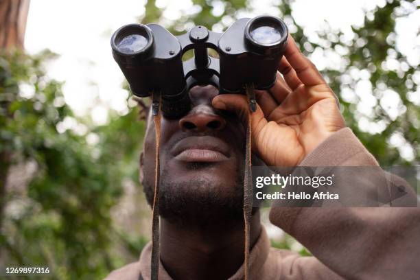 a handsome man looking at something intently through inoculars - fågelskådning bildbanksfoton och bilder