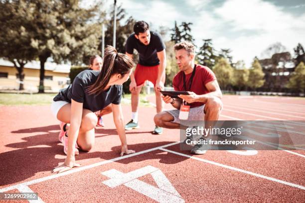 athletes reading to start on the track - running coach stock pictures, royalty-free photos & images