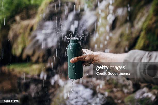 man refills his stainless steel bottle with clean and fresh water - garrafa de água garrafa imagens e fotografias de stock