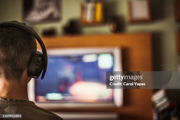 teenager boy playing video game at home - jugendkultur sitzen konsole stock-fotos und bilder