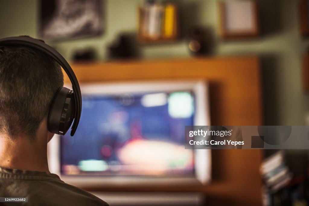 Teenager boy playing video game at home
