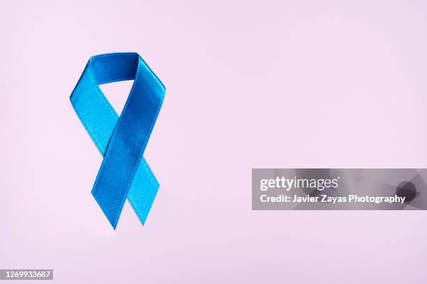 blue ribbon on pink background - colon cancer fotografías e imágenes de stock