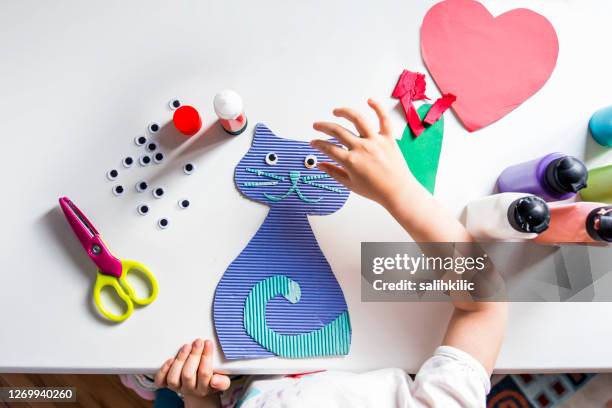 het meisje plakt googly ogen op een handgemaakt kattencijfer - kunstnijverheid stockfoto's en -beelden