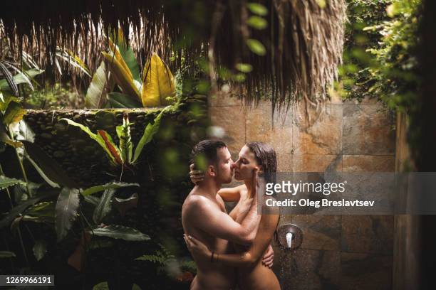 young couple in love kissing under tropical shower with passion. intimate and romantic. honeymoon in bali. - couples kissing shower stockfoto's en -beelden