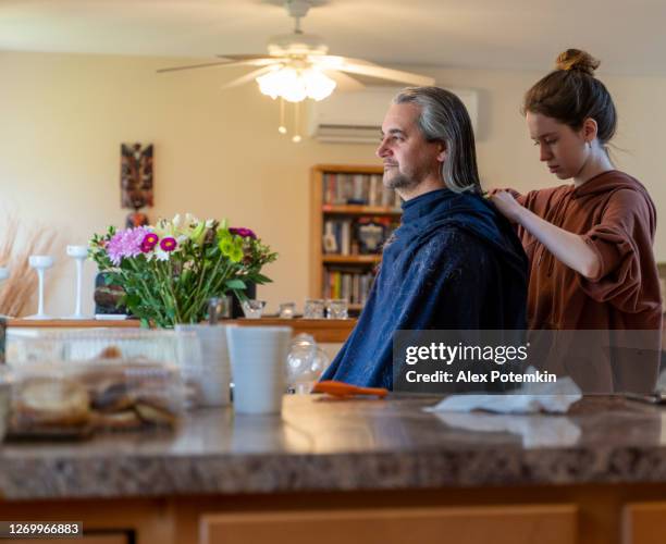 do it yourself - home haircut. late teenage girl, a daughter, gives a haircut to her father, mature 50-years-old man with long hair. - 18 19 years stock pictures, royalty-free photos & images