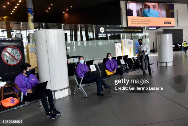 Employees of different airlines sit near the departure gate of international flights at El Dorado International Airport on August 31, 2020 in Bogota,...