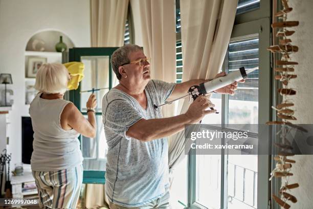 senior man en vrouw schoonmaken en caulking home windows - caulk stockfoto's en -beelden