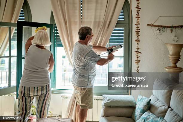 senioren schoonmaken en caulking ramen voor winterisolatie - house insulation not posing stockfoto's en -beelden