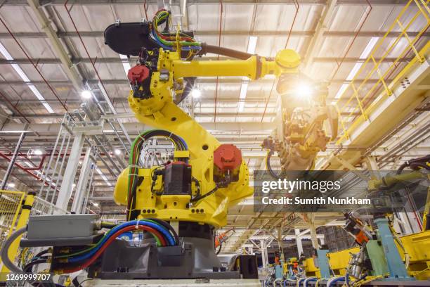 automobile plant, industrial machinery automatic arm welding cars robot in production line of vehicle manufacturer factory - robot arm stock-fotos und bilder