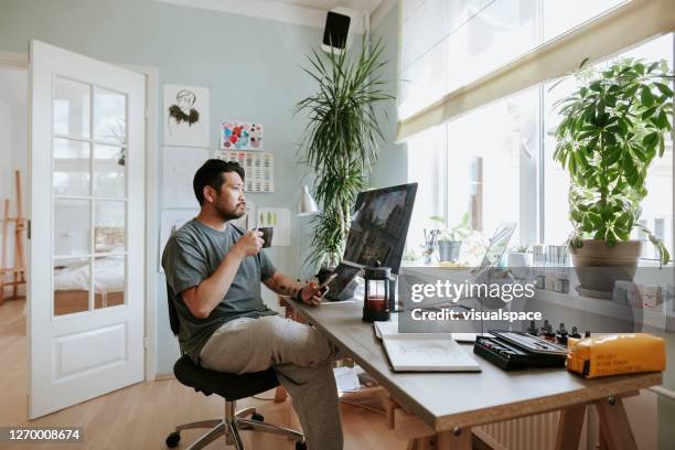 digital artist contemplates during coffee break in his home office - coffee at home imagens e fotografias de stock