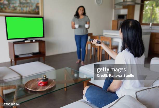 two asian woman friends watching tv at home - carrying tv stock pictures, royalty-free photos & images