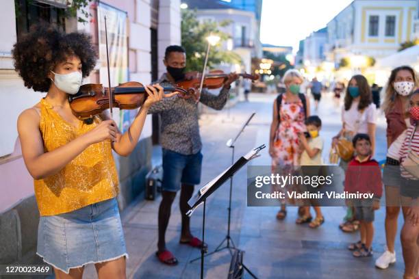 street musicians wearing face masks playing music in time of pandemic - masked musicians stock pictures, royalty-free photos & images