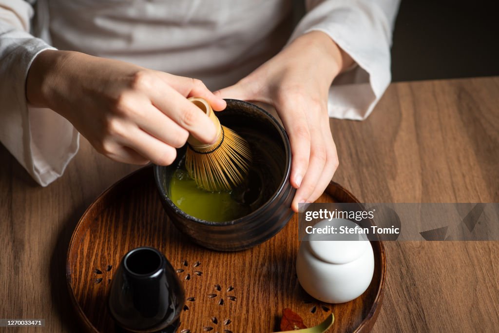 婦女攪拌火柴粉,同時製作茶茶與茶道的傳統配件的火柴綠茶。