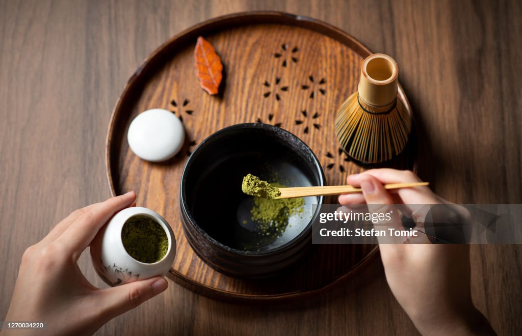 Frau macht Matcha grünen Tee mit traditionellen Accessoires für Tee-Zeremonie