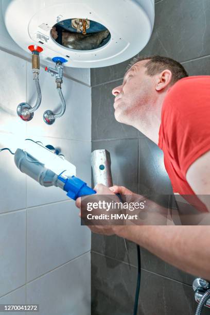 homem consertando caldeira elétrica de aquecimento tirando um aquecedor de água velho no banheiro doméstico - replacement - fotografias e filmes do acervo