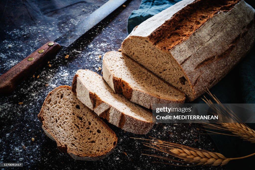 Het broodbrood van het volk dat van de volkoren met uitstekend mes over donker hout wordt gestald