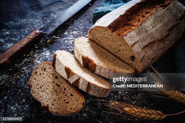 wholegrain rye bread loaf with vintage knife over dark wood - gluten free bread stock pictures, royalty-free photos & images