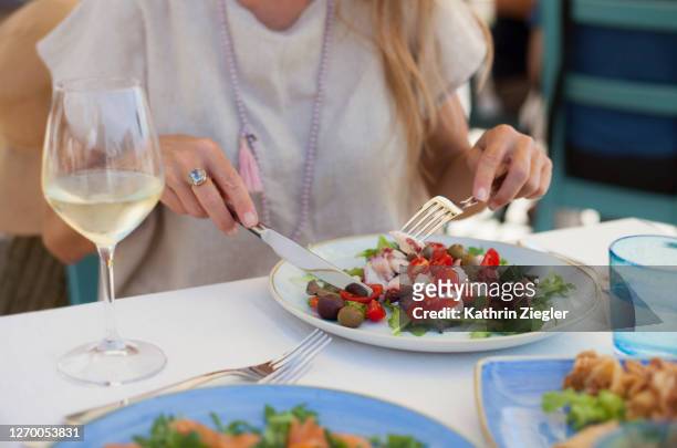 woman enjoying seafood salad and a glass of white wine, focus on plate - mediterraanse gerechten stockfoto's en -beelden