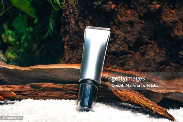 silver cosmetic tube surrounded by natural details. - cream tube stock pictures, royalty-free photos & images