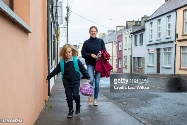 a mother and first grader walks to school on their first day back from the coronavirus pandemic - irish family stock pictures, royalty-free photos & images