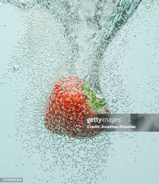 strawberry falling in fizzy water - fizz photos et images de collection