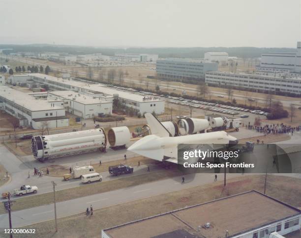 High angle view of the Space Shuttle Enterprise , passing a Saturn 1 rocket, as it heads along Rideout Road at Marshall Space Flight Center in...