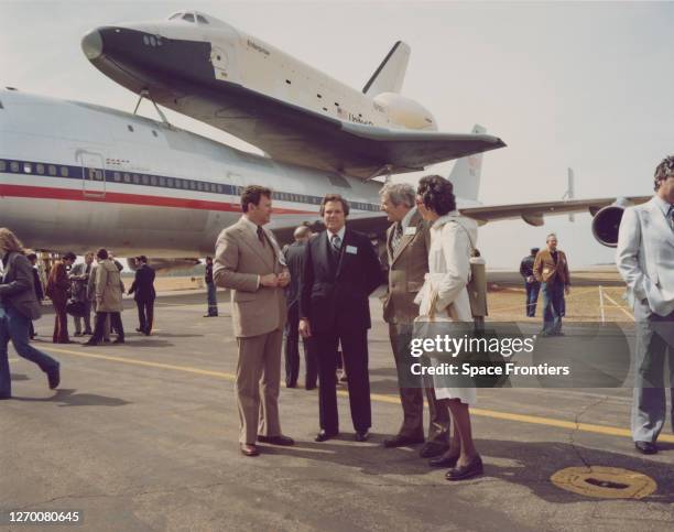 United States Congressman Ronnie Flippo among a group of people standing before Space Shuttle Enterprise atop NASA 905, a 747 carrier aircraft in the...