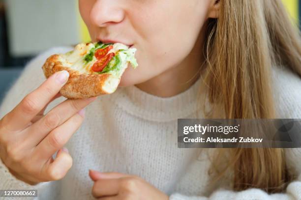 a slice of italian pizza margarita or pesto with cheese in the hands of a girl. a woman takes a slice of pizza and eats it, in a cafe or pizzeria. vegetarian food. fast food. - eating pesto stock pictures, royalty-free photos & images