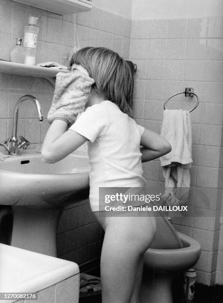 Petite fille se nettoyant le visage au gant de toilette, circa 1980, France.