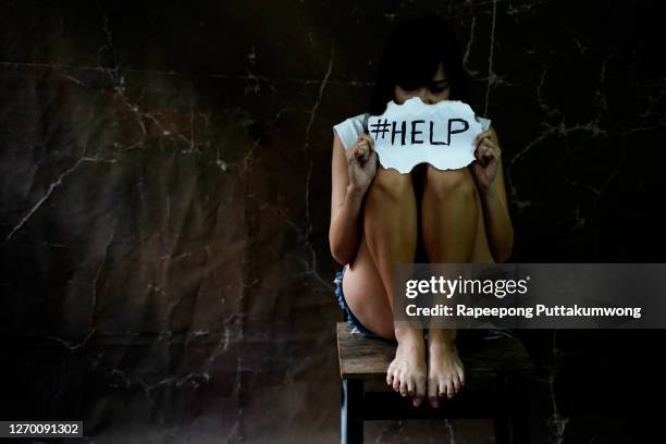 woman sitting on chair and holding a plaque with the inscription about the help. inscription against domestic violence. - domestic violence stock pictures, royalty-free photos & images