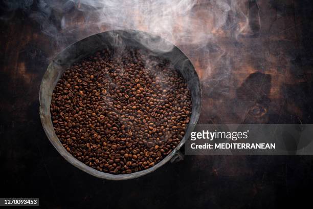 medium roasted coffee beans smoky in roasting pan on wood - arabica coffee drink stock pictures, royalty-free photos & images