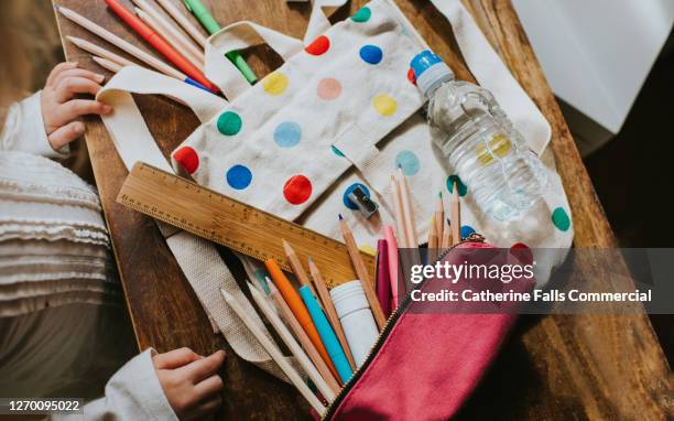 child looking at a spotty schoolbag with stationary surrounding - etui stockfoto's en -beelden