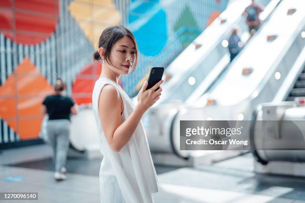 young woman using smart phone at subway station - one young woman only photos et images de collection