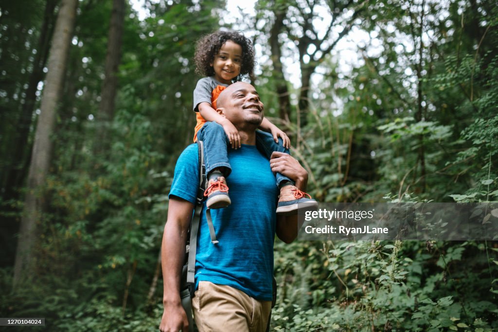 Padre lleva a su hijo en caminata a través de sendero forestal en el noroeste del Pacífico