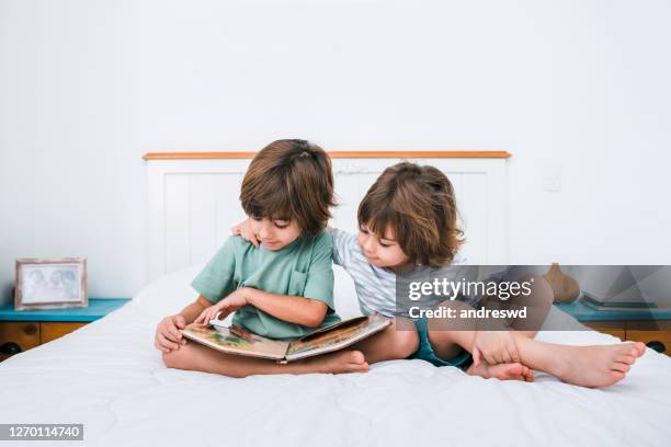 due bambini che leggono libro in camera da letto - famiglia con due figli foto e immagini stock