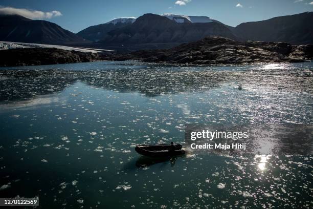 Ice melts near Nordenskjodbreen glacier as man past by with a boat on August 25, 2020 on the Norwegian Arctic Svalbard archipelago, Norway....